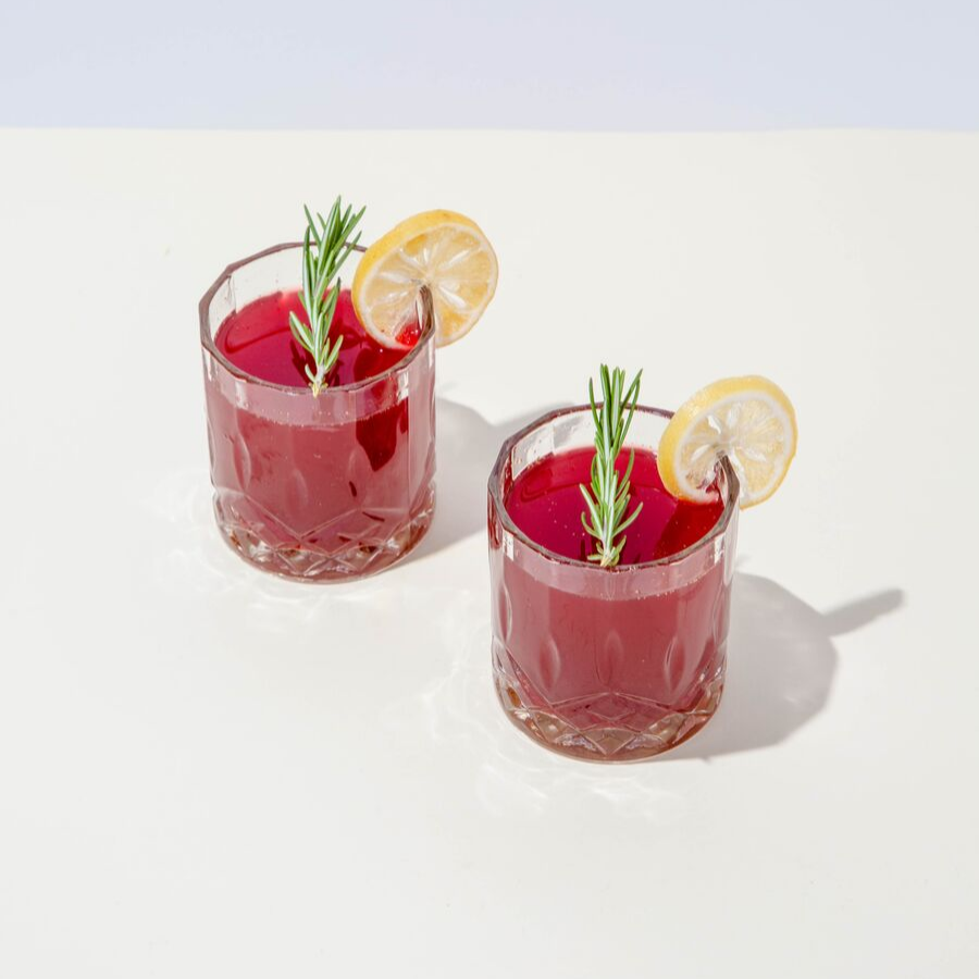 top view of two glasses of ginger beet martini topped with sliced lemon and rosemary