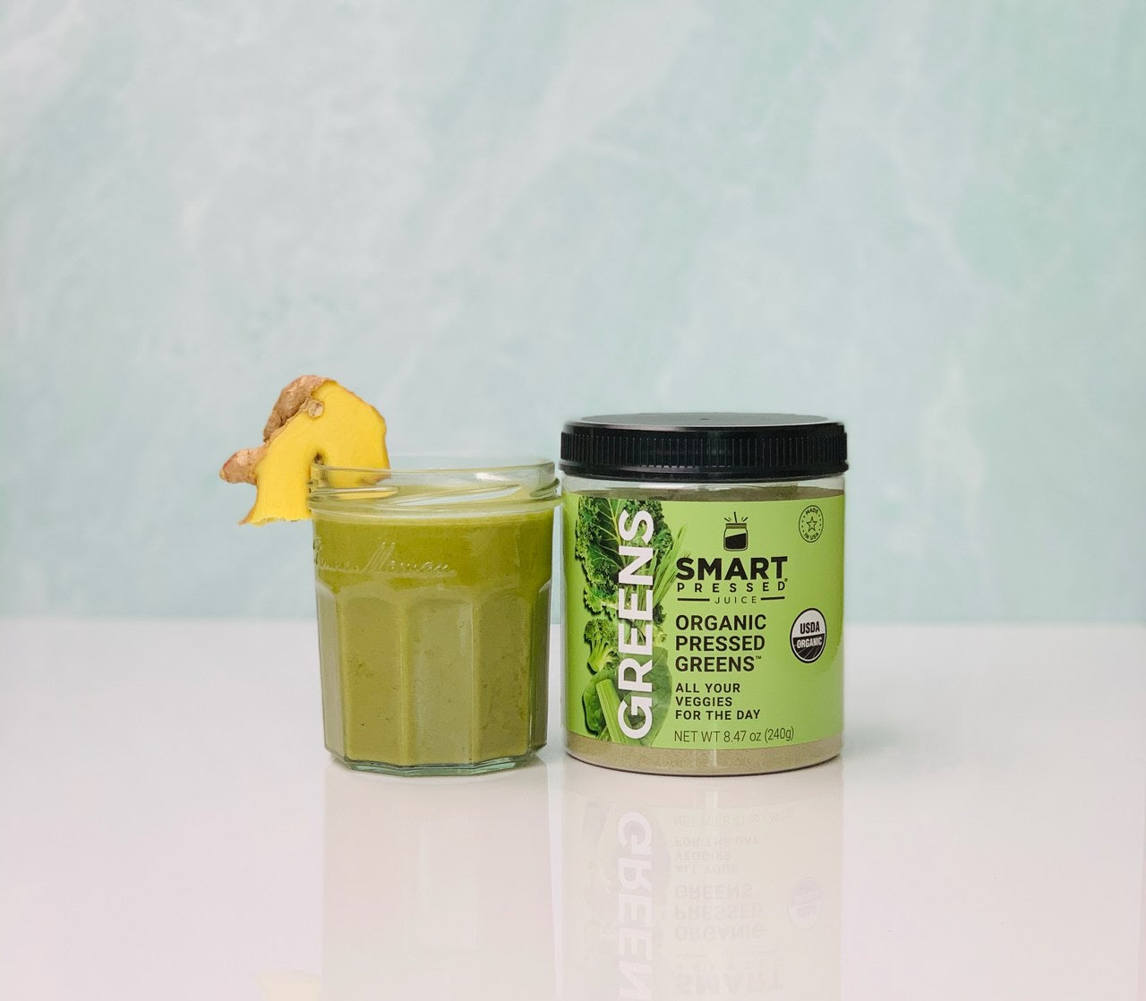 a glass of Immunity Greens Juice with a smart pressed label organic pressed greens on top of a white table