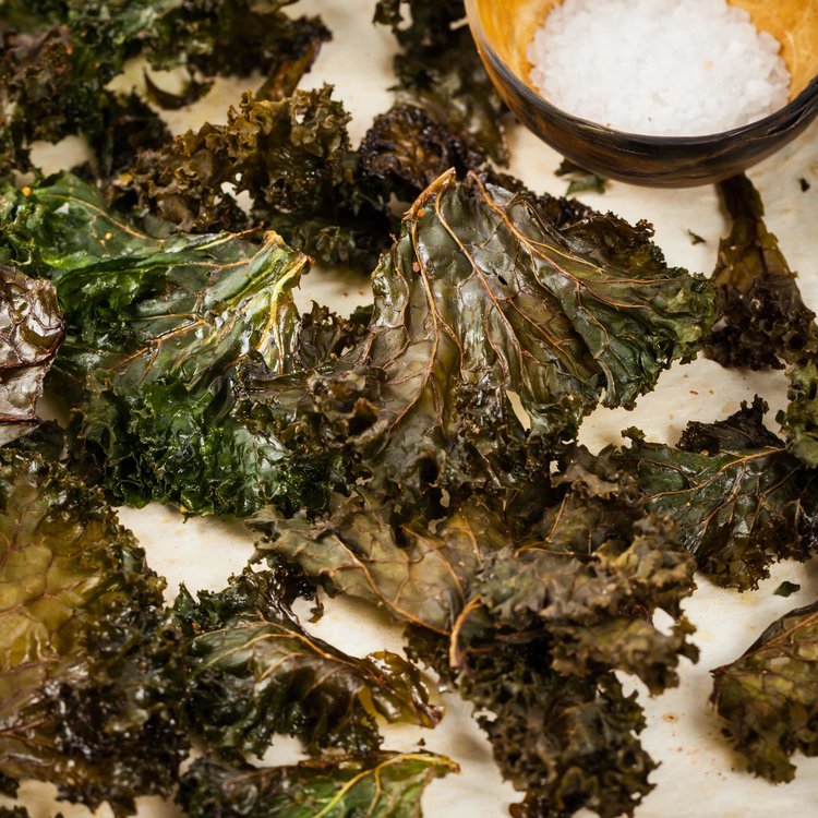 baked kale leaves beside a bowl of rock salt.