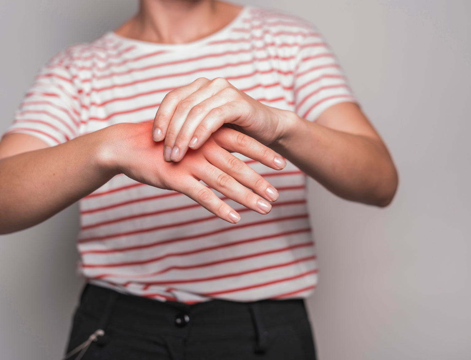 young woman having pain in hand against gray background