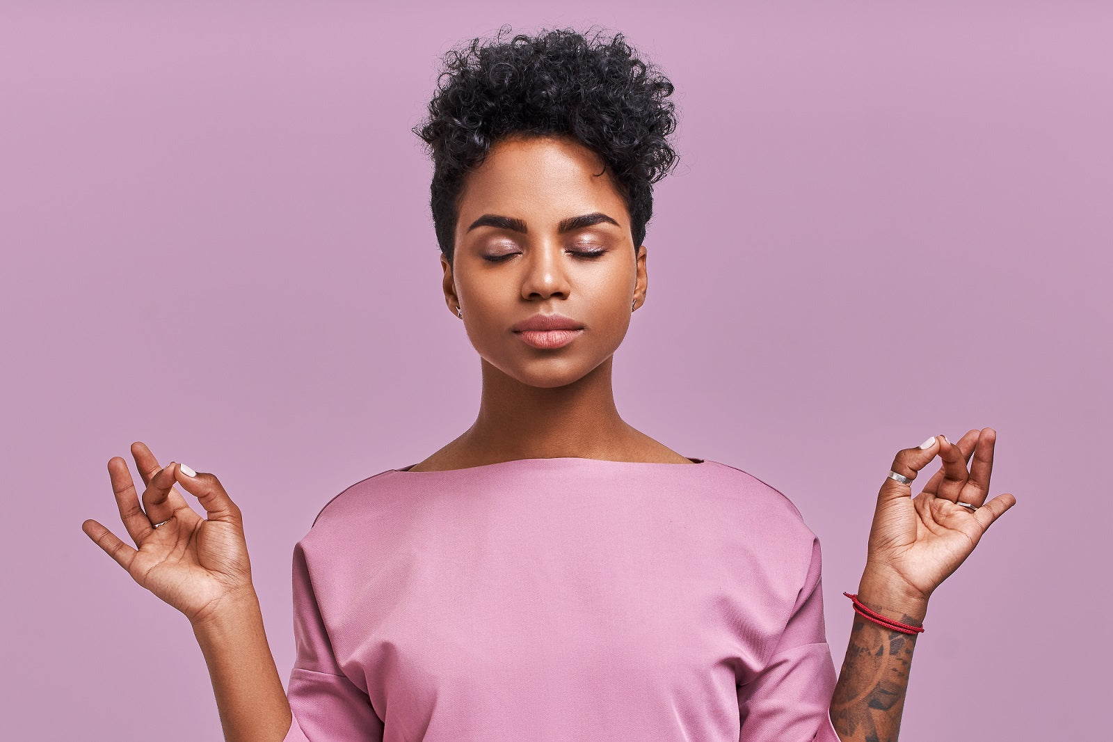 woman meditating in a pink shirt on a matching pink background