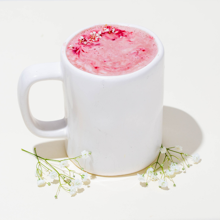 a cup of strong brewed beets latte sprinkled with clove and nutmeg on top surrounded with small white flowers side by side