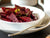 a bowl of sliced beet root garnished with green herbs with a fork on the side.