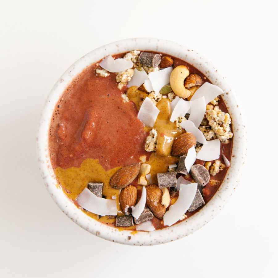 top view of chocolate beets smoothie bowl topped with choco bits, almonds, cashew, rice flakes, and coconut chips