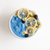 top view of blue dream proteini smoothie bowl topped dried slices of lemon and three berries and small white flowers