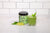 front view of a glass of Signature Greens Smoothie topped with mint and a jar of smart pressed organic pressed green with two slices of lime on top of mint leaves on top of a white painted table