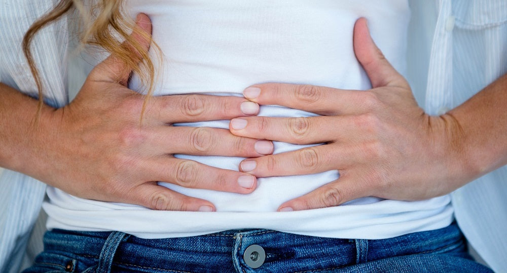 A half-body woman holding her stomach with her both hands.