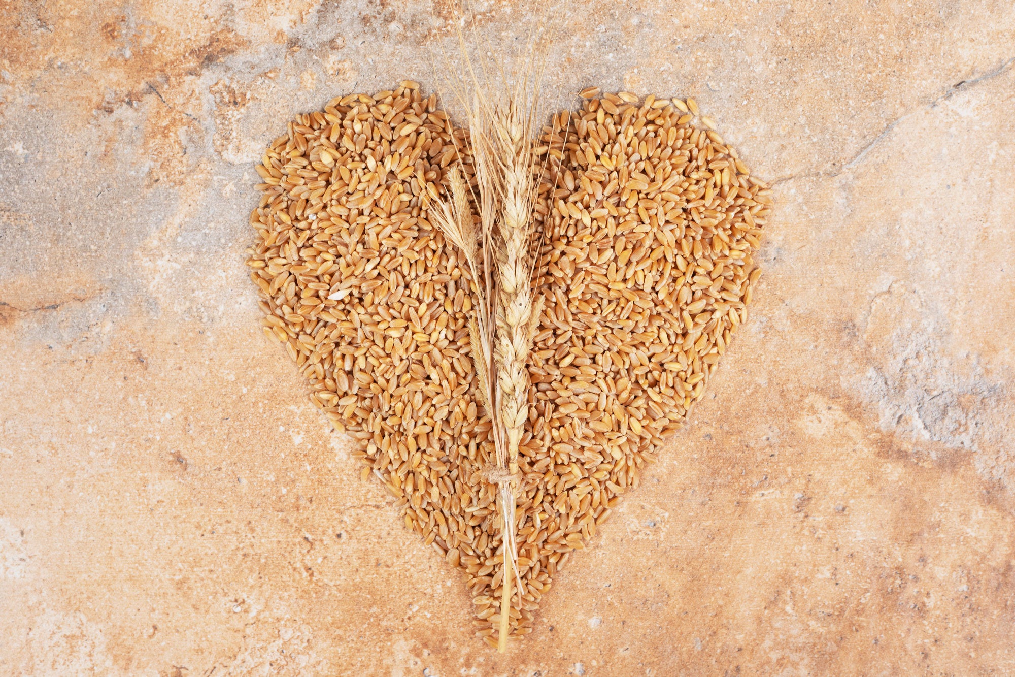 Image of a bunch of barley shaped into a heart on a marble surface.
