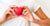 Image of a person in a white T-shirt holding a red heart replica against his right chest.