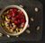 top view of chocolate cherry whole-grain bowl of barley, rye, oats, and lentils surrounded by pistachio nuts on top of a black table cloth on top of a black table