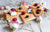 five heart-shaped waffles on top of a white chopping board with berries on top of it surrounded by flowers and a fork on the side