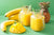 2 mason jars of Mango Banana Cleanse next to a pineapple, sliced mango, and bananas