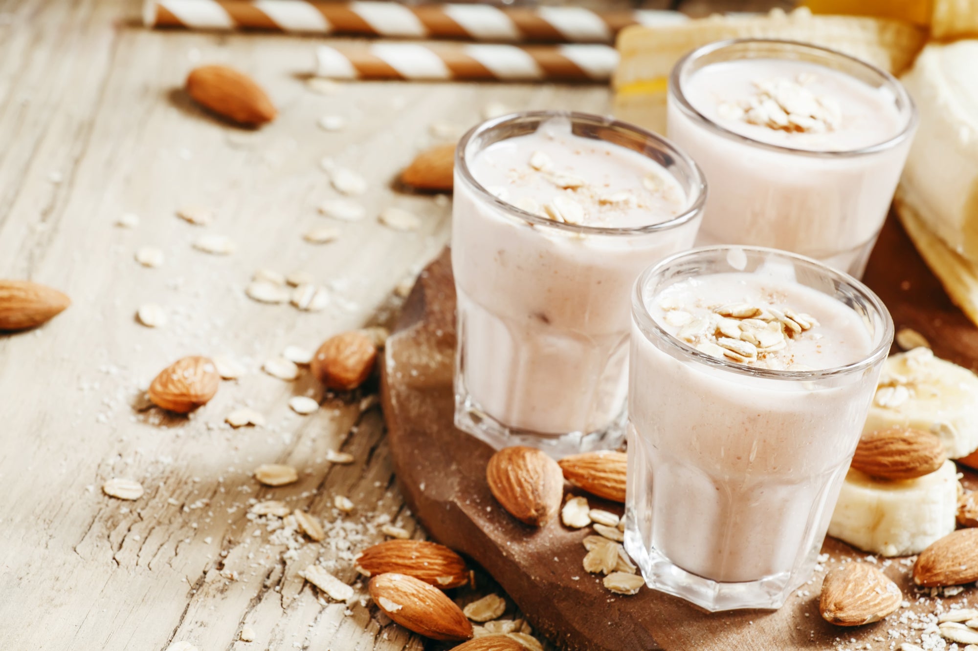 3 glasses of Almond Butter Proteini surrounded with  almonds