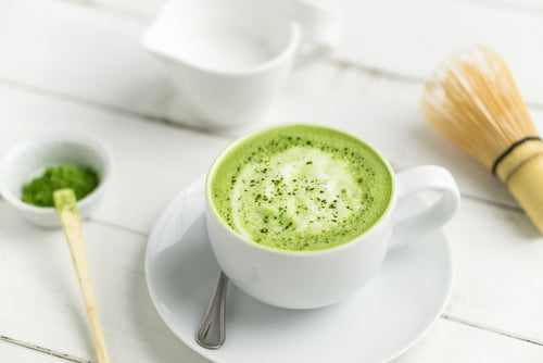 a cup of Wendy's Warming Green Matcha Latte with teaspoon next to a creamer and matcha powder